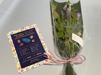納涼例会プチコンサートのパンフレットと小さな草花の花束